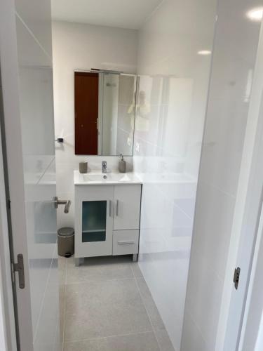 een witte badkamer met een wastafel en een spiegel bij BENALMADENA ALOHA PLAYA BEACH LOFT in Benalmádena