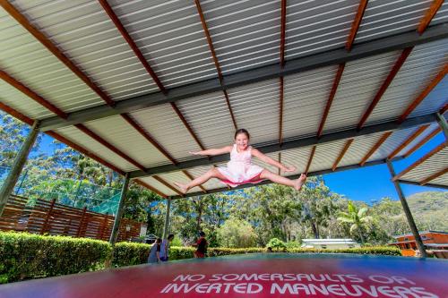 a girl is jumping on a trampoline at NRMA South West Rocks Holiday Park in South West Rocks