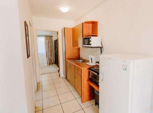 a small kitchen with a refrigerator and a microwave at Golden Candle Guest House in Roodepoort