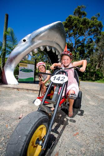 two children are riding on a toy car at NRMA South West Rocks Holiday Park in South West Rocks