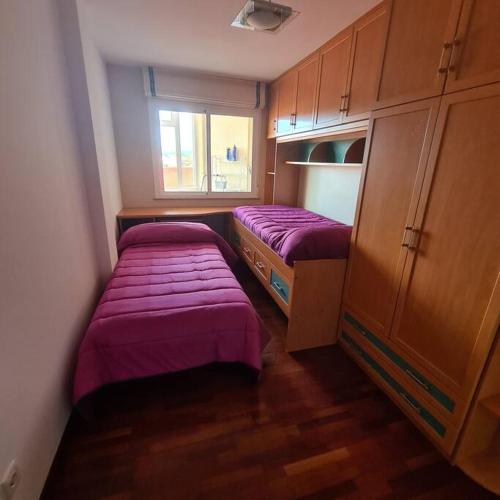 duas camas num pequeno quarto com lençóis roxos em piso en noia em Noya