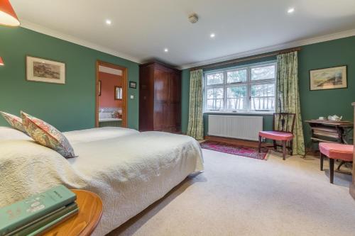 a bedroom with green walls and a bed and a desk at Grooms Cottage C in Grimston