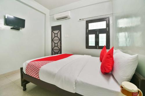 una camera da letto con un letto con cuscini rossi e una TV di Flagship Hotel Bliss a Kota
