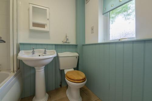 a bathroom with a sink and a toilet and a window at Sea Wind in Brancaster