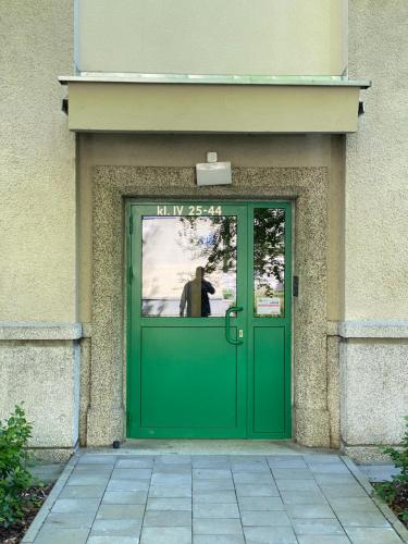 a man is standing behind a green door at Apartament Osiedle Ogrodowe in Kraków
