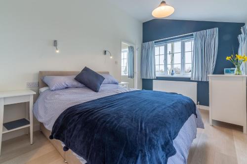 a blue bedroom with a bed with a blue blanket at Little Lammas in Ringstead