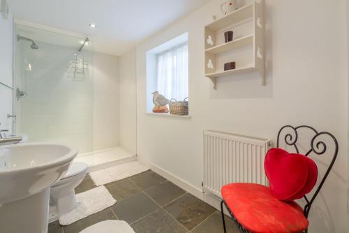 a bathroom with a red chair in front of a sink at Angel Cottage in Little Walsingham