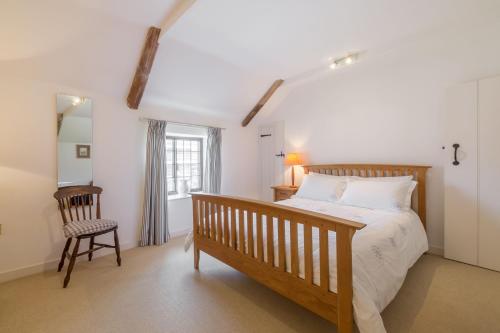 a bedroom with a bed and a chair and a window at Angel Cottage in Little Walsingham