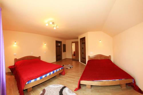 a bedroom with two beds with red sheets at Pensiunea Sarah Bran in Bran