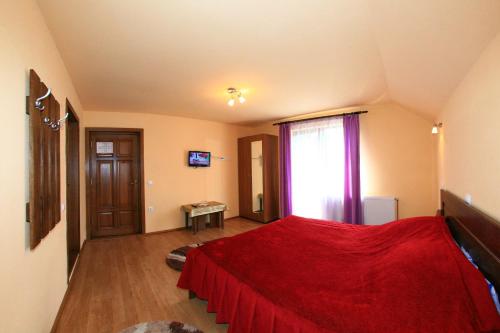 a bedroom with a red bed and a window at Pensiunea Sarah Bran in Bran