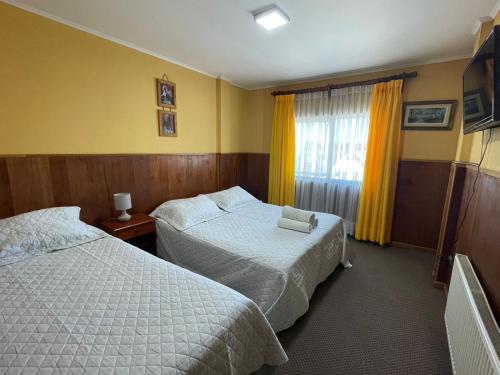 a hotel room with two beds and a window at Hotel Costa del Mar in Puerto Montt