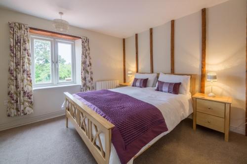 Un dormitorio con una cama grande y una ventana. en Skimming Stones, en North Creake