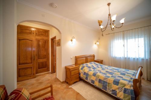 a bedroom with a bed and a chandelier at A típica casa de férias in Parchal