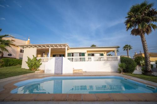 a villa with a swimming pool in front of a house at A típica casa de férias in Parchal