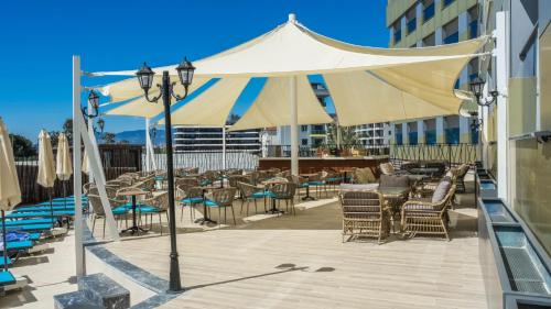 a large white umbrella on a deck with chairs and tables at Kırbıyık Resort Hotel - Alanya in Kargicak