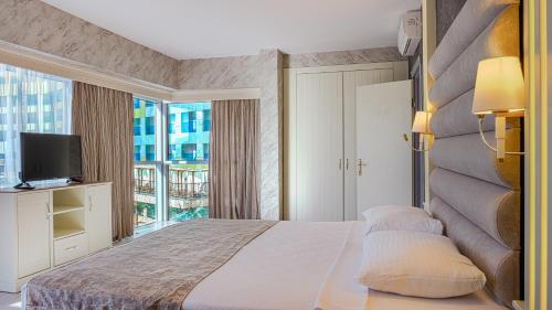 a bedroom with a bed and a large window at Kırbıyık Resort Hotel - Alanya in Kargicak