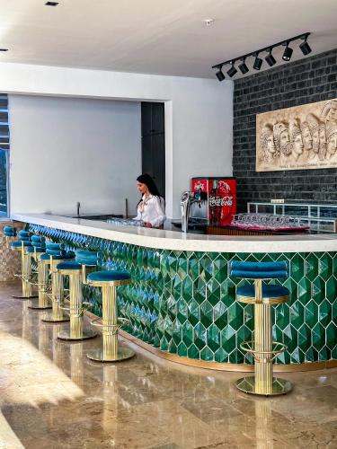 a woman standing behind a bar with stools at Kırbıyık Resort Hotel - Alanya in Kargicak