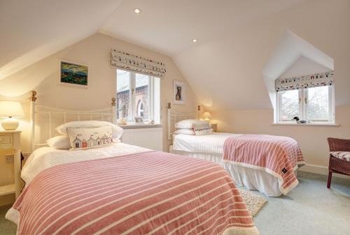 two beds in a room with two windows at The Manse in South Creake