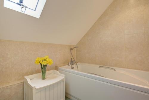 a bathroom with a tub and a vase of yellow flowers at The Manse in South Creake