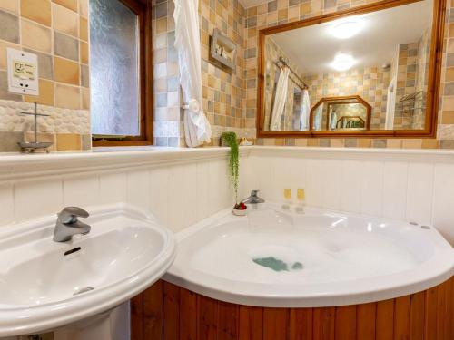 ein Badezimmer mit einem weißen Waschbecken und einem Spiegel in der Unterkunft Woodlands in Milverton