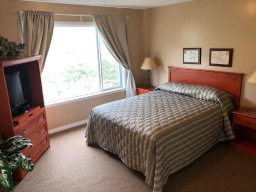 een slaapkamer met een bed, een televisie en een raam bij Paradise Canyon Golf Resort, Luxury Villa 409 in Lethbridge