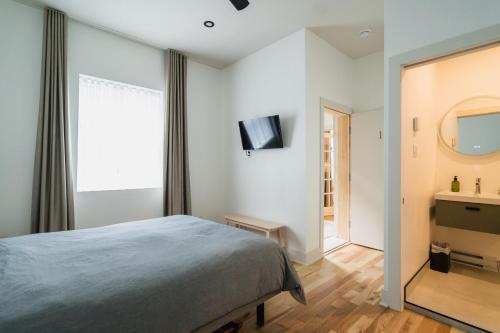 1 dormitorio con cama, espejo y TV en Bed and Breakfast du Village BBV, en Montreal