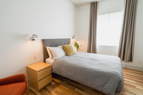 a bedroom with a bed and a chair and a window at Bed and Breakfast du Village BBV in Montréal