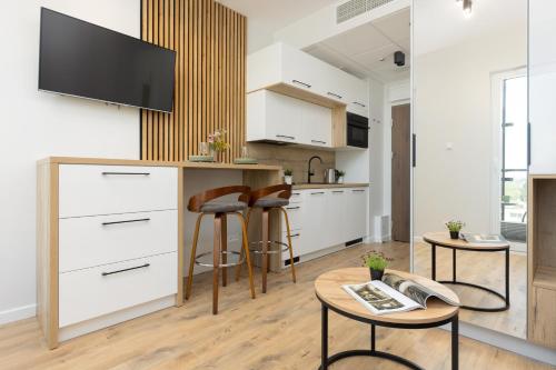 a kitchen with white cabinets and a table and stools at Wola Business Studios Kasprzaka by Renters in Warsaw