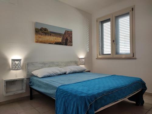 - une chambre avec un lit doté d'un couvre-lit bleu dans l'établissement Appartamenti Carneo Torre San Giovanni - Verso sud, à Torre San Giovanni