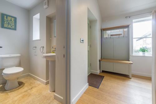 a bathroom with a toilet and a sink and a window at Caddows in Docking