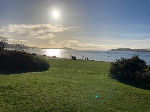 a field with the sun setting over the water at The Waterside Apartment 6 in Largs