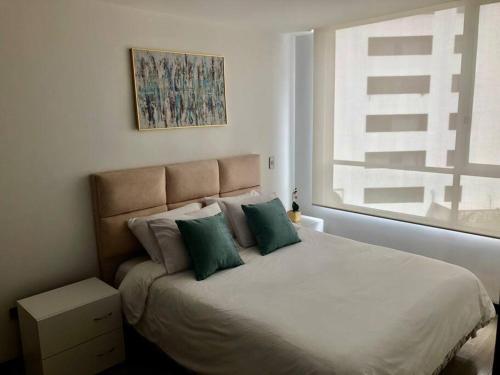 a bedroom with a large bed with green pillows at Suite en la mejor zona de Quito in Quito