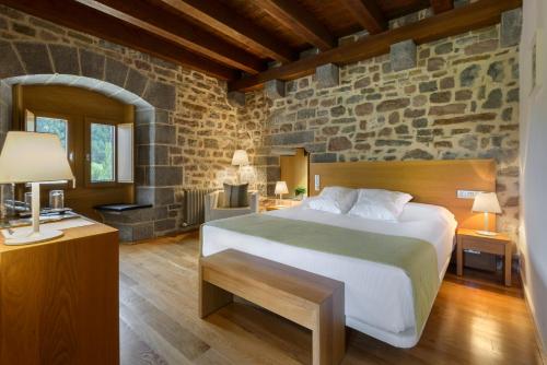 a bedroom with a bed and a stone wall at Hotel Rural Torre de Úriz in Uriz