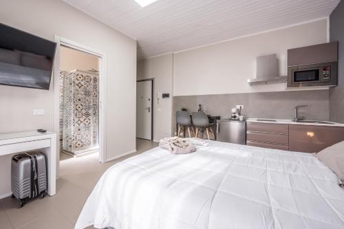 a bedroom with a large white bed and a kitchen at Suite 649 Mono con terrazzo in Modena