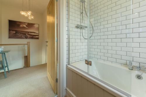 een badkamer met een bad en een douche bij Sea Holly Cottage in Thornham