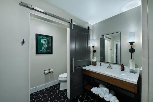a bathroom with a sink and a toilet and a mirror at Oxford Suites Paso Robles in Paso Robles