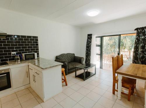 a kitchen and living room with a table and a couch at Golden Candle Guest House in Roodepoort
