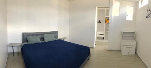 a white bedroom with a blue bed and a hallway at Plaza Tababela near Quito Airport in Quito