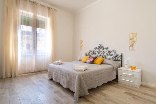 a white bedroom with a large bed and a window at Piombino Apartments - Casa Collodi in Piombino