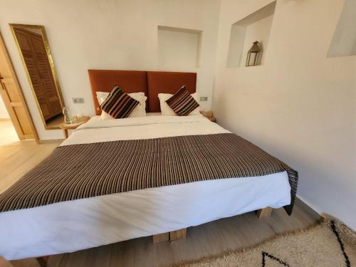 a bedroom with a large bed with a wooden headboard at AdaZen Ecolodge in Azilal