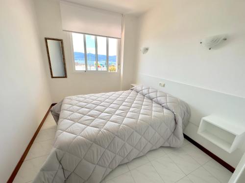 Habitación blanca con cama y ventana en Apartamentos Park Raxo, en Raxó