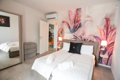 a bedroom with a large white bed with a painting on the wall at Sunset Lodge - ENJOY HOLIDAY in Garda