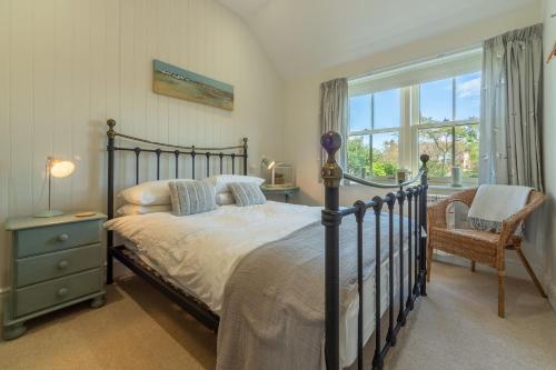 a bedroom with a bed and a chair and a window at Wigeon Cottage in Thornham