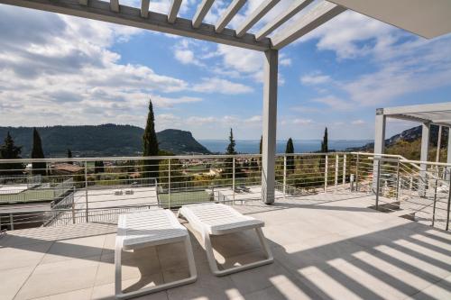 a patio with two white chairs and a pergola at Sunset Lodge - ENJOY HOLIDAY in Garda