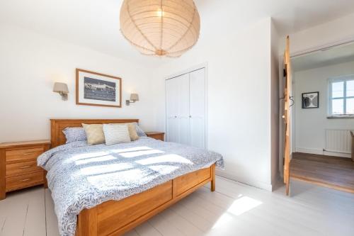 a bedroom with a bed and a chandelier at Marigold Cottage in Docking