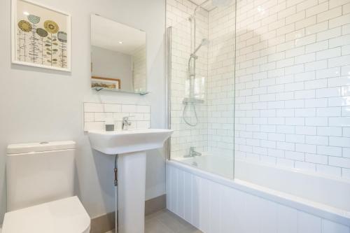 a white bathroom with a sink and a toilet at Marigold Cottage in Docking