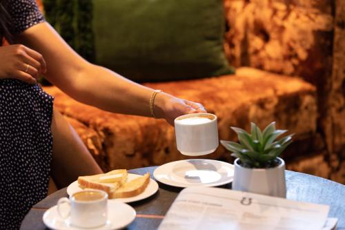 a woman sitting at a table with a cup of coffee at Oxford Suites Paso Robles in Paso Robles