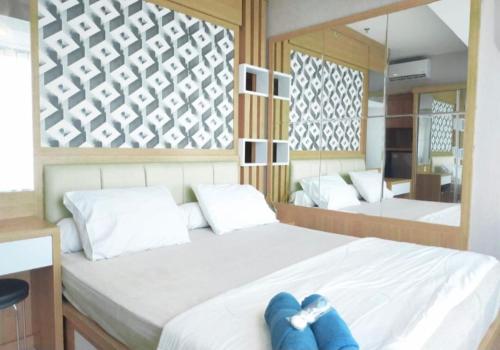 ein Schlafzimmer mit einem Bett mit zwei blauen Kissen darauf in der Unterkunft Apartemen grand kamala lagoon in Kayuringin