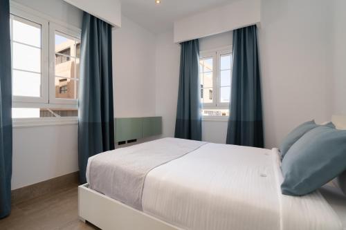 sypialnia z białym łóżkiem z niebieskimi zasłonami w obiekcie Sabbia Suites La Armada w mieście Arrecife