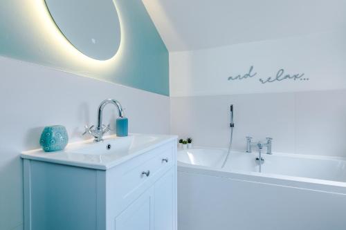 a bathroom with a sink and a tub and a mirror at Pyecroft Cottage in Chester